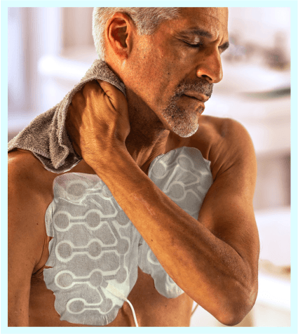 Man mit Optune Lua-Transducer-Arrays auf der Brust trocknet sich den Hals mit einem Handtuch ab.