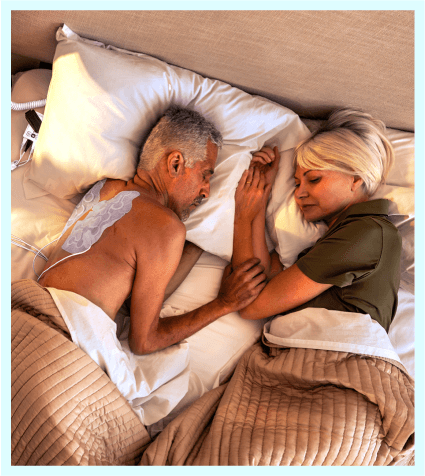 Man mit Optune Lua-Transducer-Arrays schläft neben einer Frau im Bett.